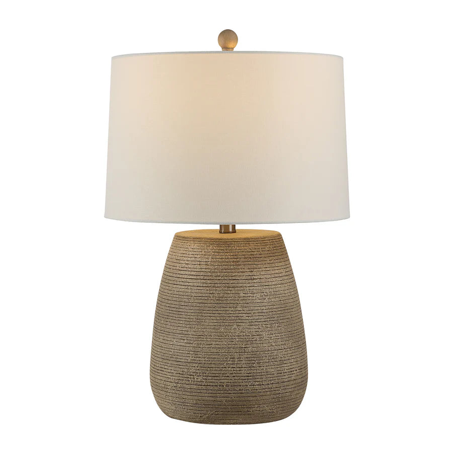 Table lamp with textured base and beige shade on a white background