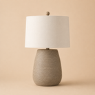 Table lamp with textured resin base and white shade on a beige background