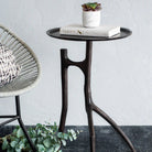 Small black side table with a plant and books on a gray rug