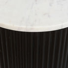 Round side table with marble top and black base on a white background