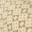 Close-up of a fabric with a green geometric pattern on a beige background