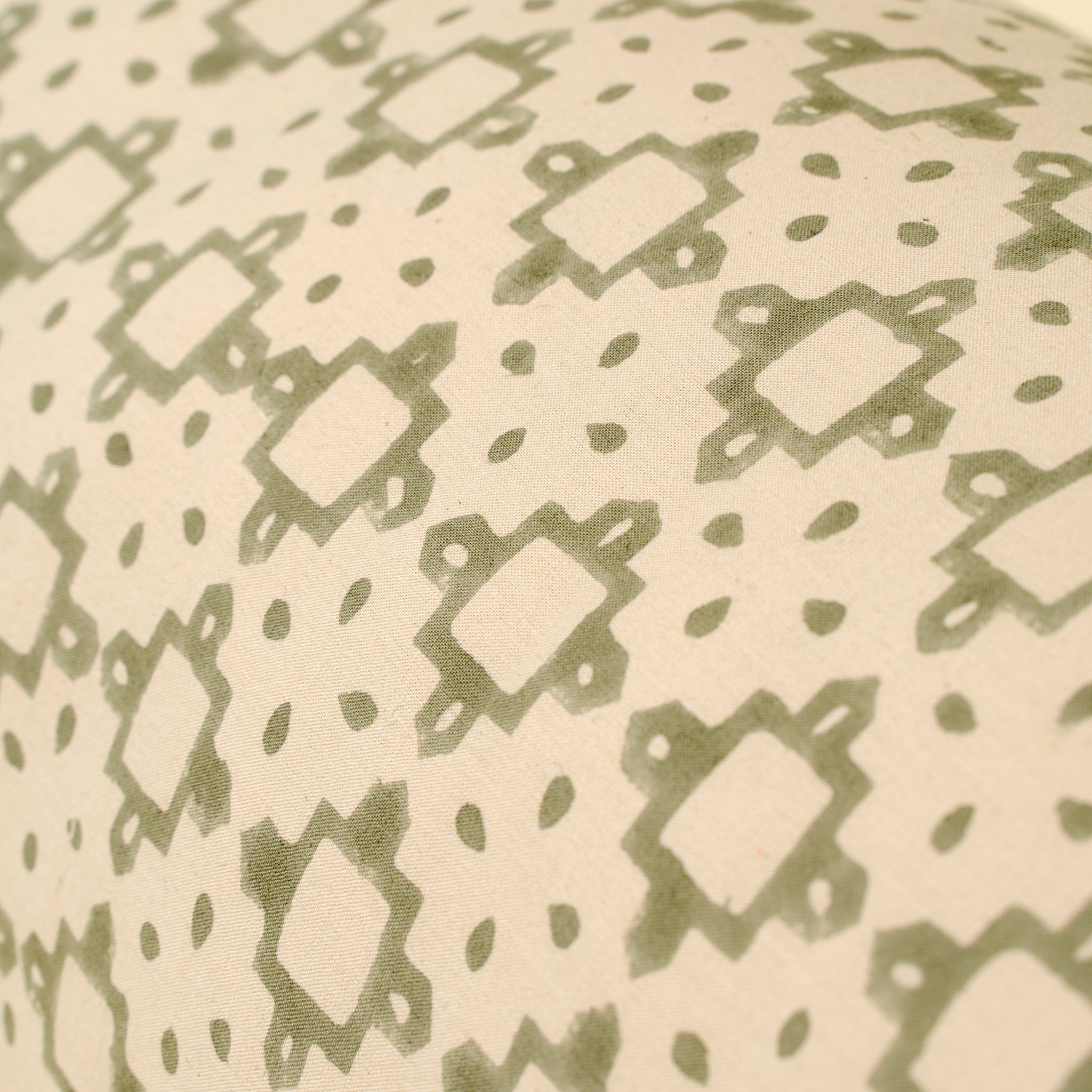 Close-up of a fabric with a green geometric pattern on a beige background