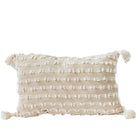 Beige pillow with white pattern and tassels on a white background