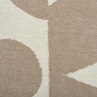 Close-up of a patterned rug with geometric shapes in beige and brown.