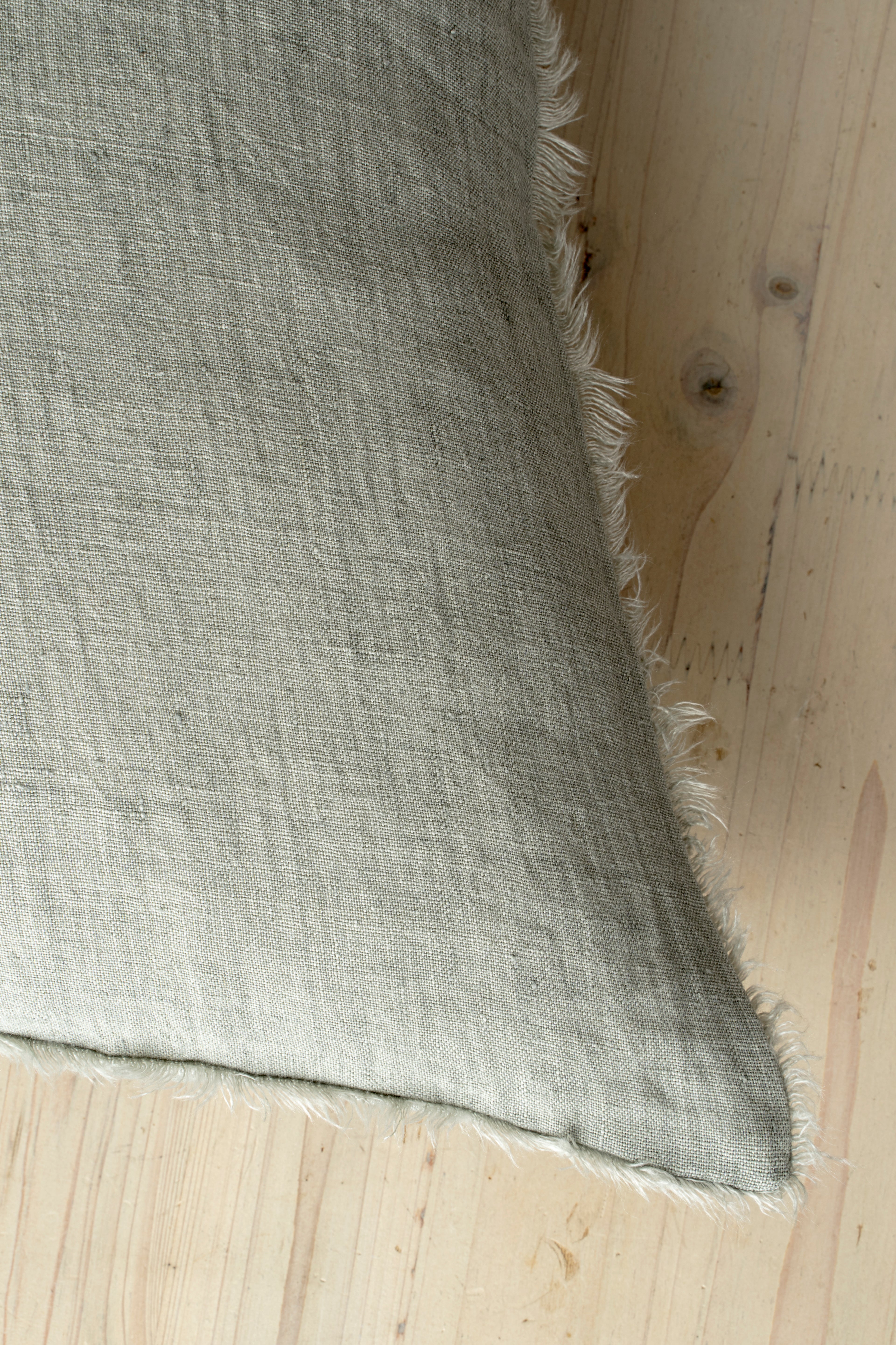 Macro close-up of the Lina linen pillow showcasing the breathable fabric and the delicate frayed fringe edge