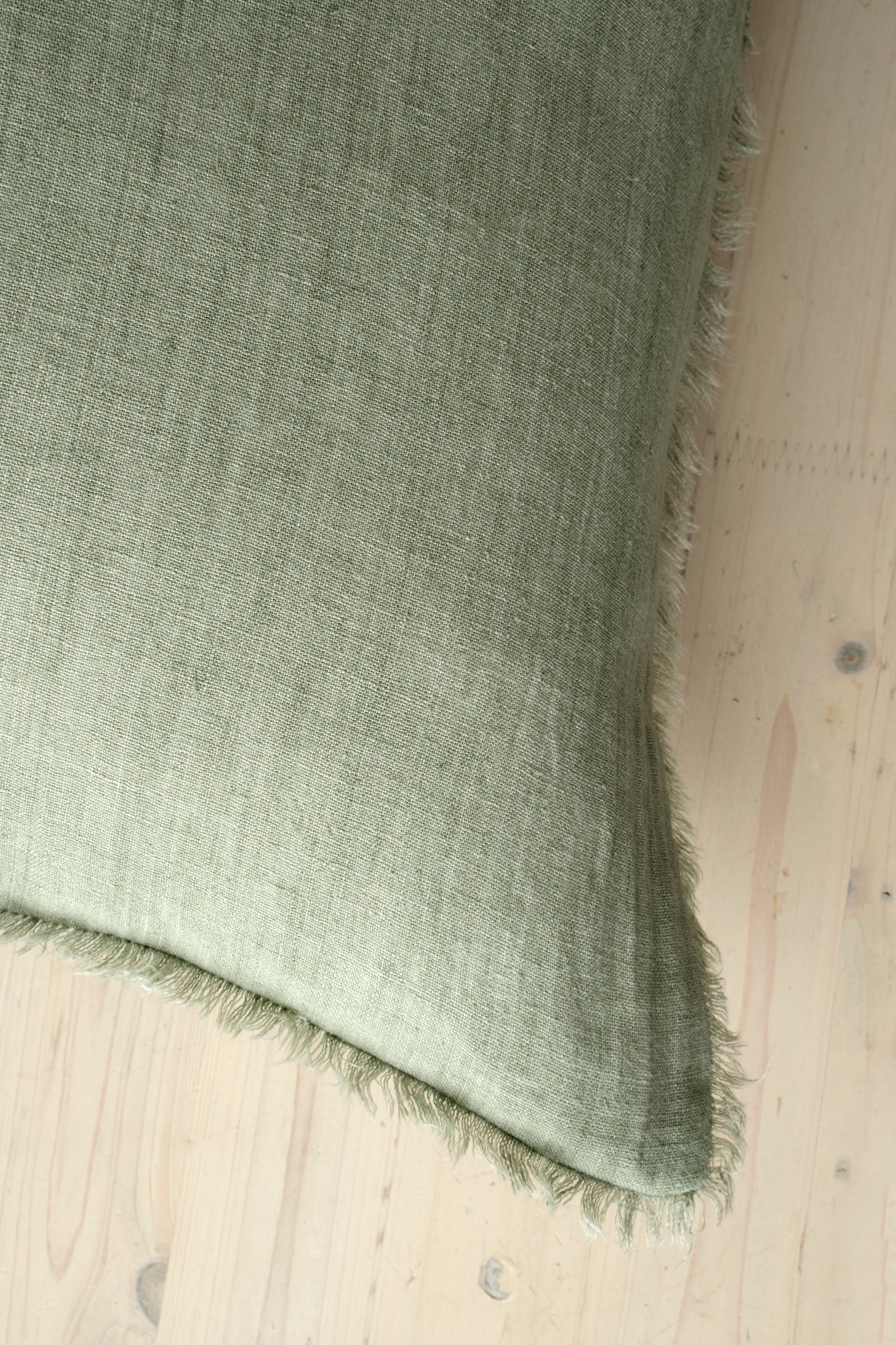 Macro close-up of the Lina linen pillow showcasing the breathable fabric and the delicate frayed fringe edge