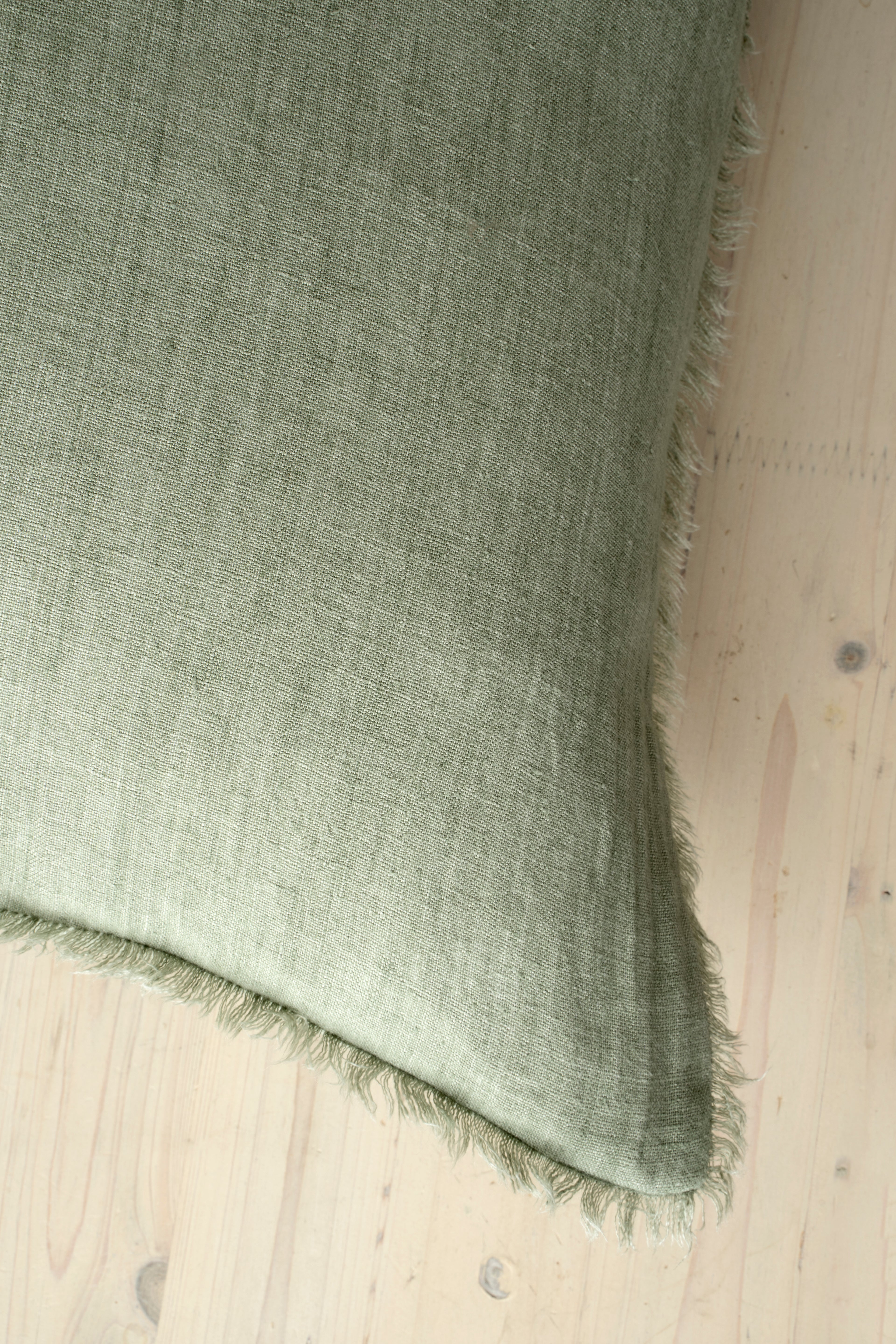 Macro close-up of the Lina linen pillow showcasing the breathable fabric and the delicate frayed fringe edge