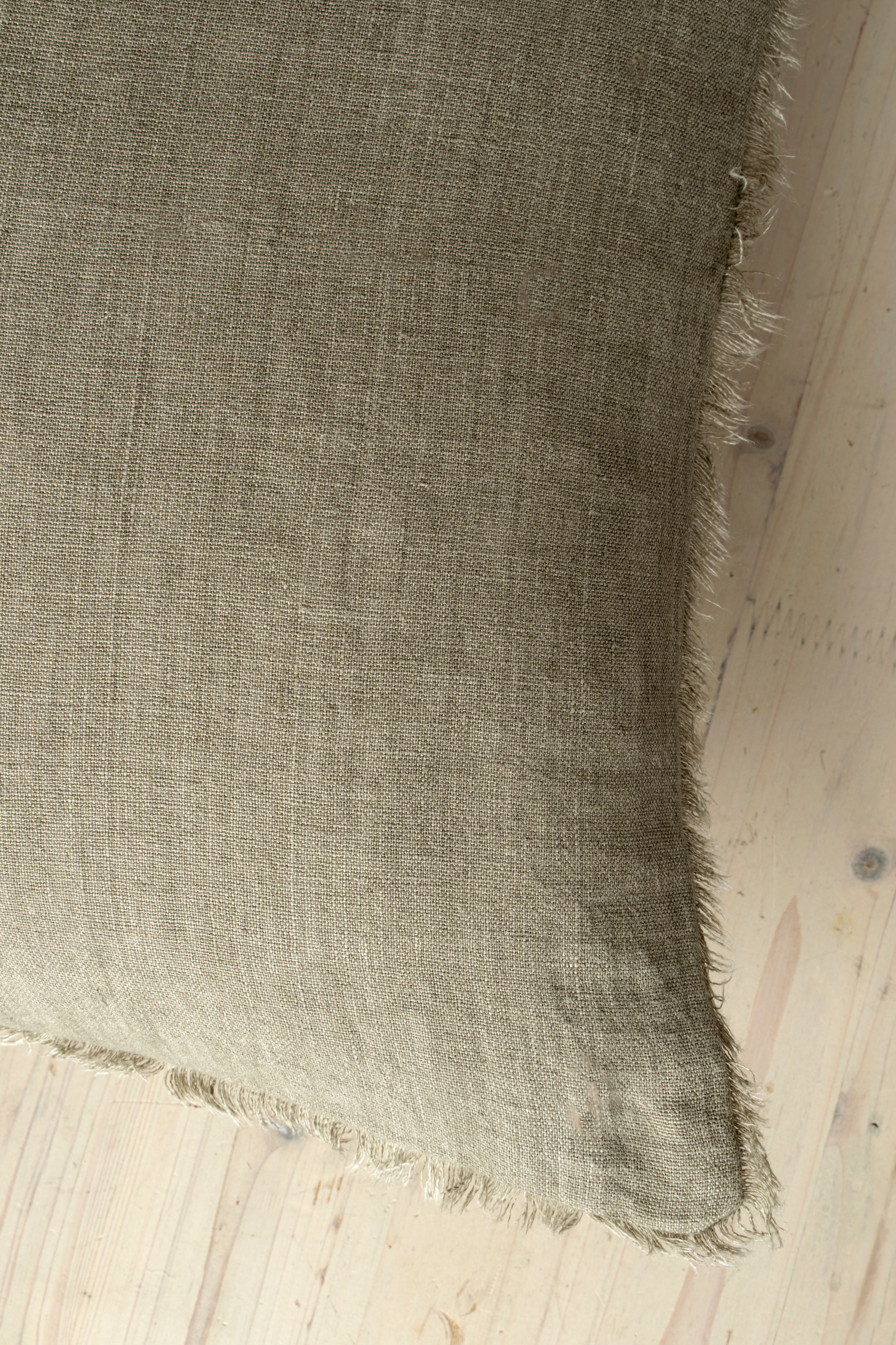 Macro close-up of the Lina linen pillow showcasing the breathable fabric and the delicate frayed fringe edge