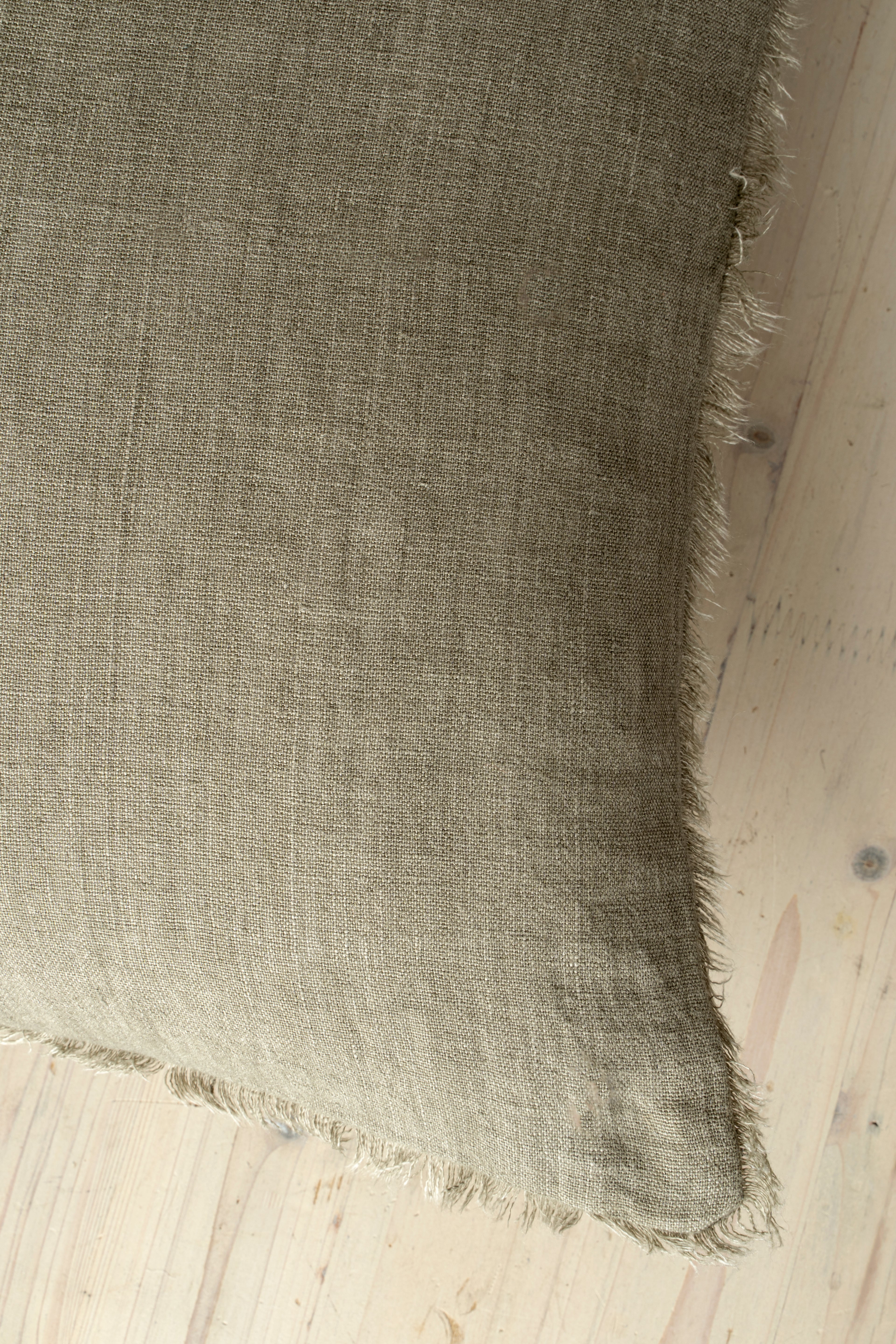 Macro close-up of the Lina linen pillow showcasing the breathable fabric and the delicate frayed fringe edge