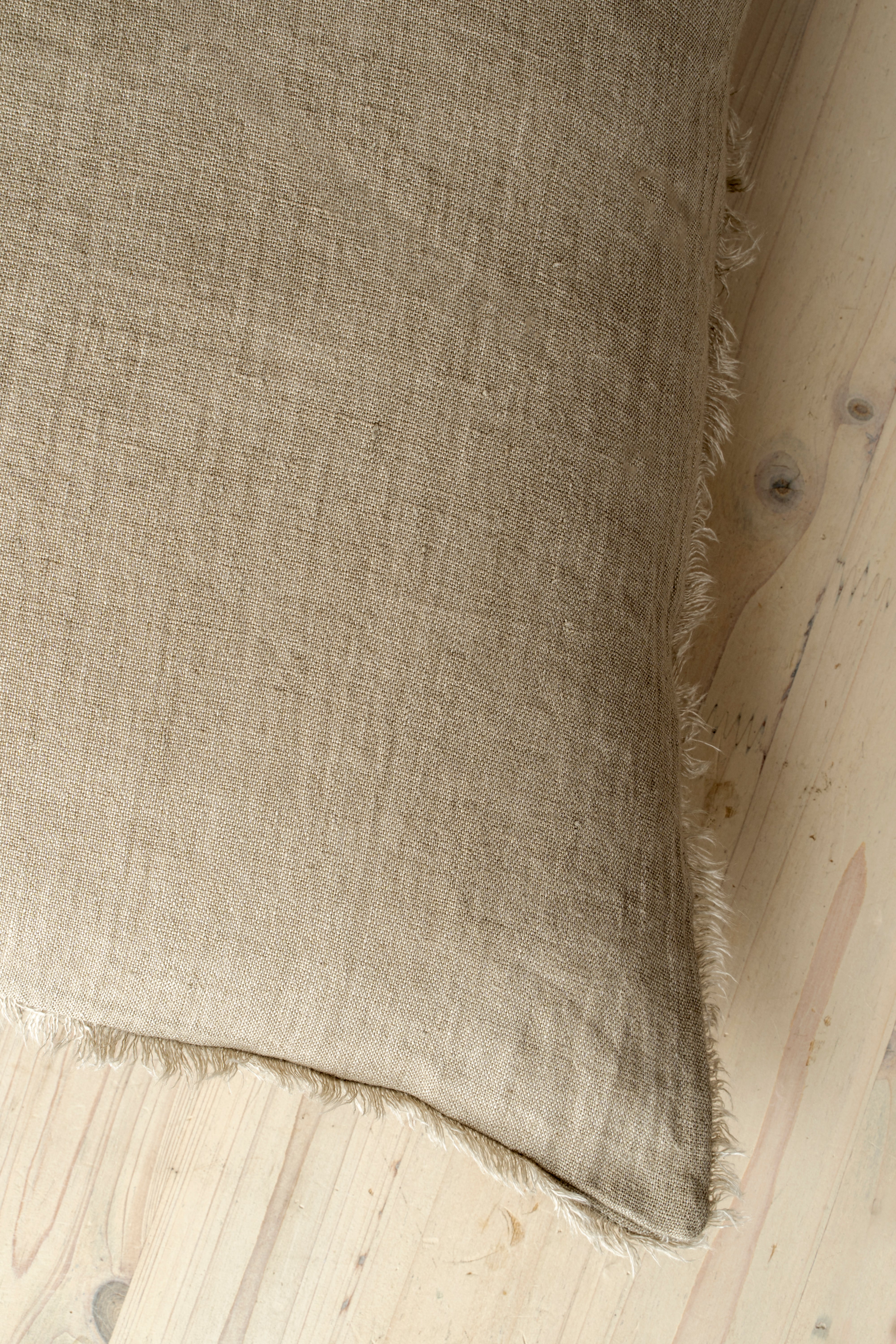 Macro close-up of the Lina linen pillow showcasing the breathable fabric and the delicate frayed fringe edge