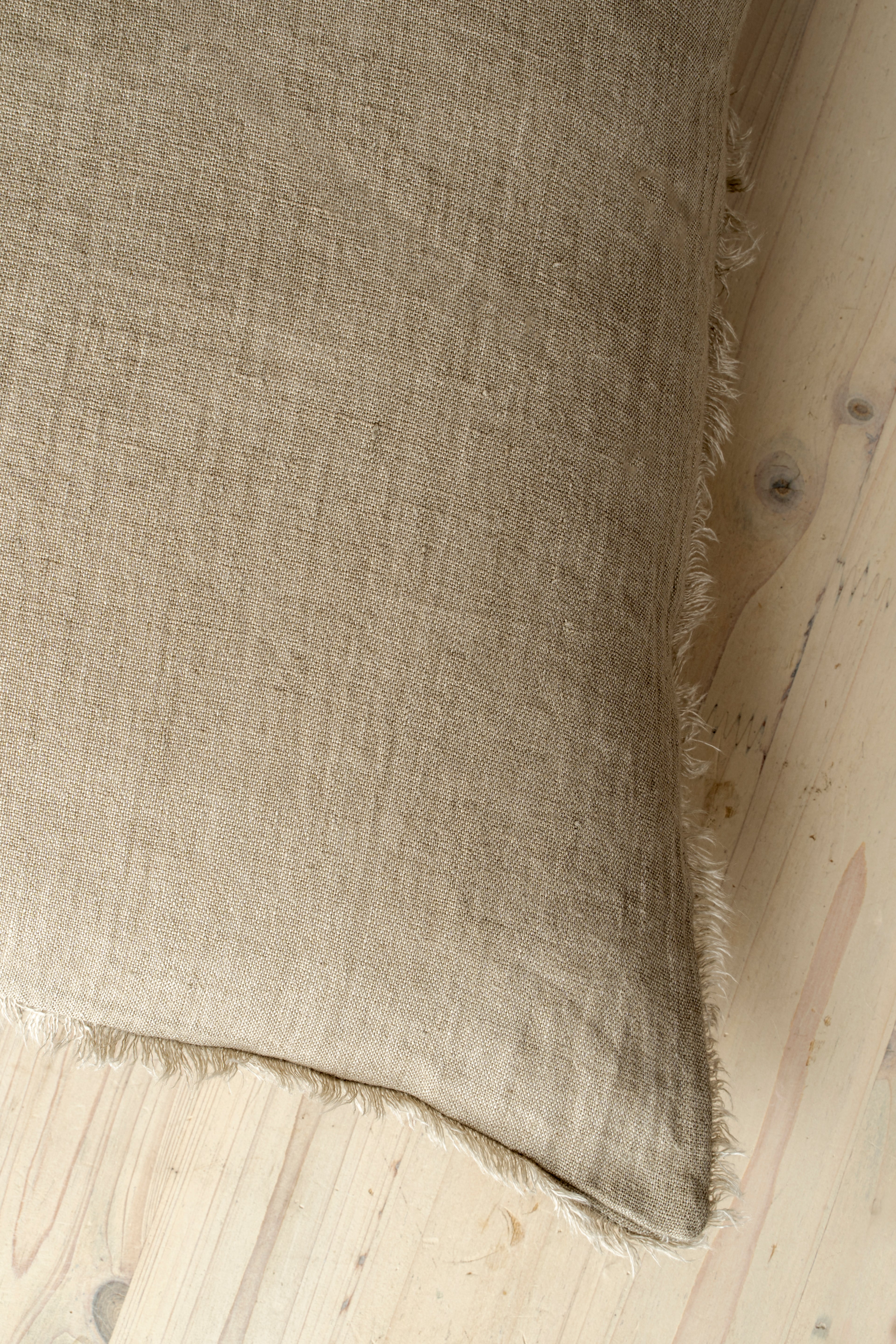 Macro close-up of the Lina linen pillow showcasing the breathable fabric and the delicate frayed fringe edge