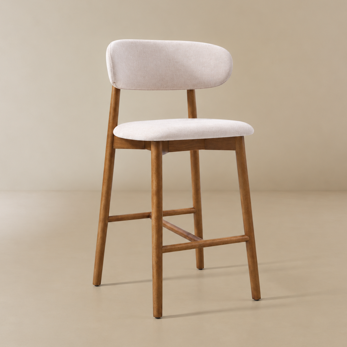Linen ash wood bar stool with a light beige upholstered seat and backrest, supported by a warm medium-brown wooden frame with a curved top rail and footrest, set against a solid beige background.