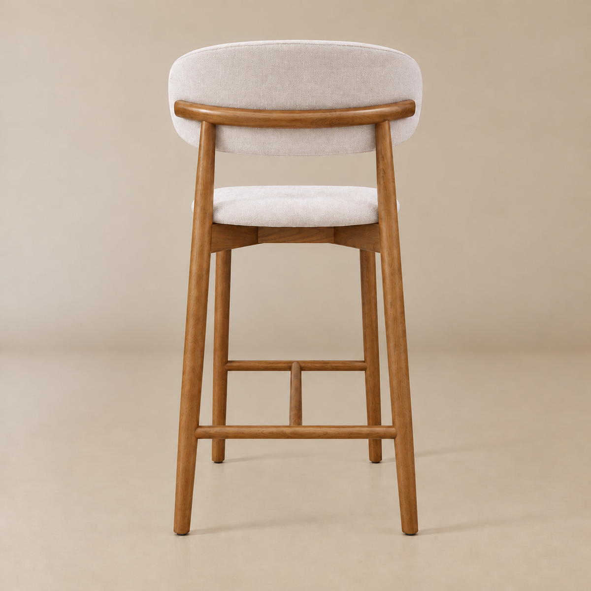 Linen ash wood bar stool with a light beige upholstered seat and backrest, supported by a warm medium-brown wooden frame with a curved top rail and footrest, set against a solid beige background.