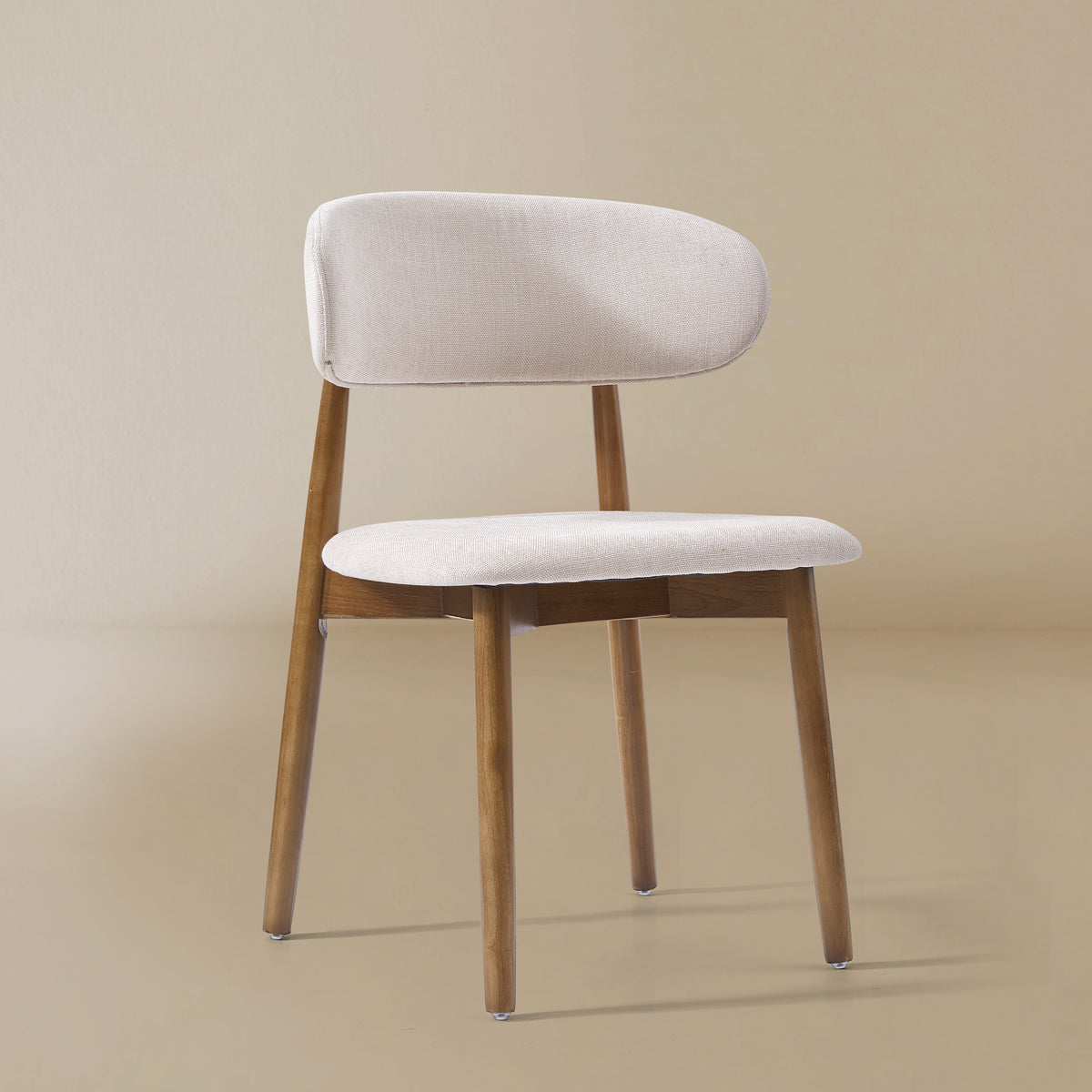 Angle view of the Linen Ash Wood Dining Side Chairs with curved upholstered backs and ash wood frames, shown in a neutral studio setting