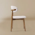 Side profile view of the Linen Ash Wood Dining Side Chairs with curved upholstered backs and ash wood frames, shown in a neutral studio setting
