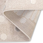 Folded corner view of the Little Roar Kids Rug showing neutral dot details and woven backing.