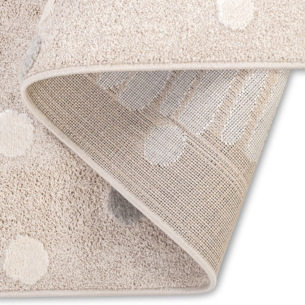 Folded corner view of the Little Roar Kids Rug showing neutral dot details and woven backing.