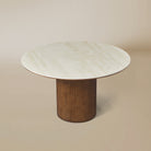 Lucia Dining Table with round sintered stone top and fluted cylindrical wood base styled in a neutral studio setting