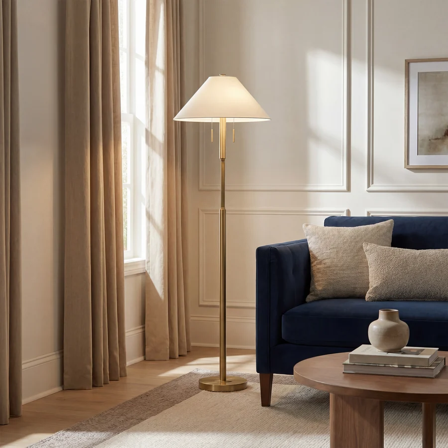 Lucienne Antique Brass Floor Lamp styled beside a blue sofa in a warm, refined living room.