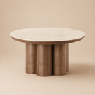 Full view of the Lyric coffee table featuring a round cream sintered stone top and walnut finish clustered cylinder base.
