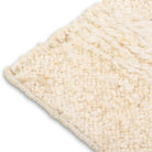 Close-up corner detail of the Maeve rug showing the neat edge binding and the contrast between the flatweave base and raised nubby wool pile.
