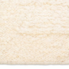 Macro detail of the Maeve hand-woven rug surface highlighting the ultra-textured, chunky nubby wool pile in warm cream.