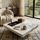 Modern living room with a marble coffee table, armchair, and large window.