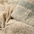 Close-up of textured fabric with natural tones and a tassel.