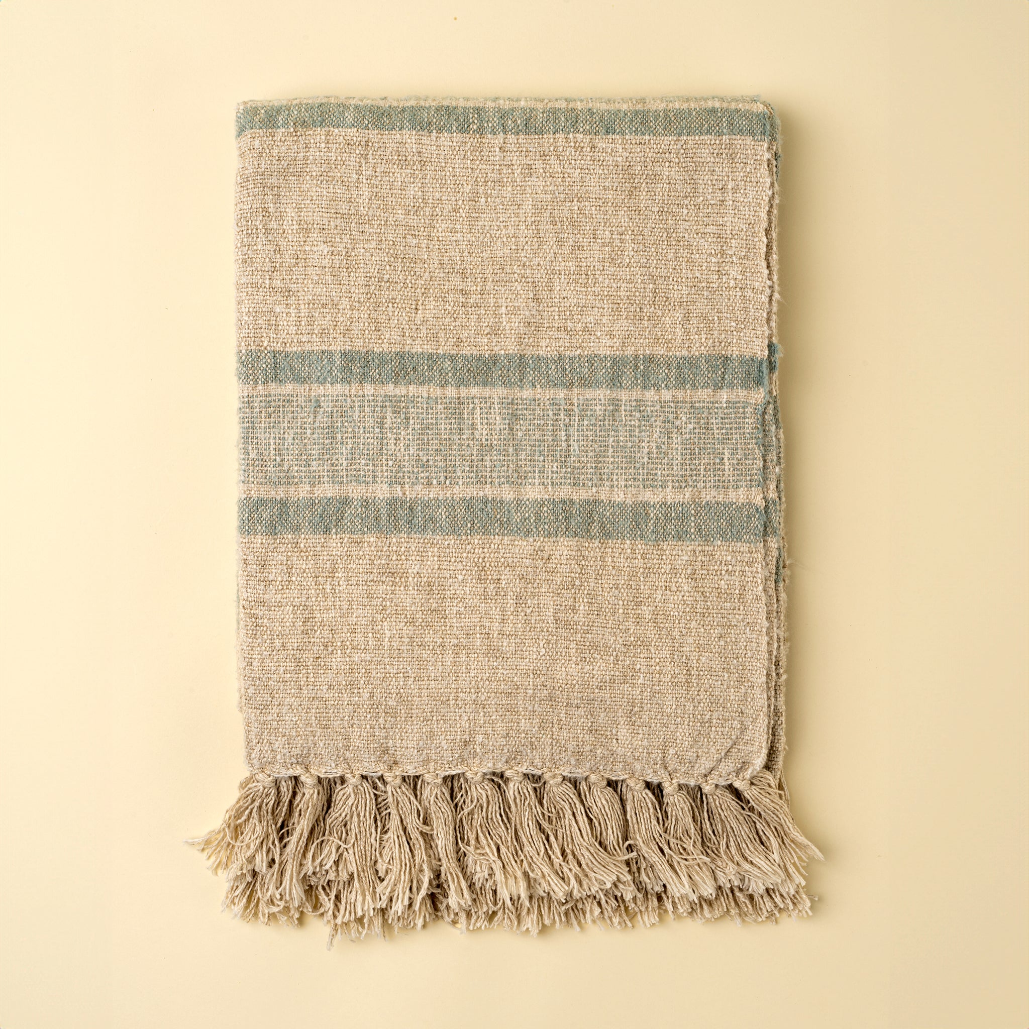 Textured throw blanket with fringes on a beige background