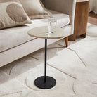 Small round side table with a black base and wooden top in a living room setting.
