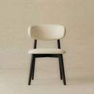 Full front view of the Modern Leather Ash Wood Dining Side Chair featuring a cream seat and a curved backrest with a matte black wood finish.
