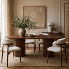 Dining room with wooden table and chairs, vase with greenery, and framed artwork on the wall.