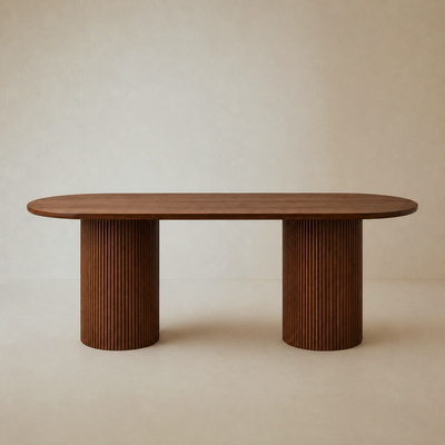 A modern oval dining table with a medium brown wood top and two fluted cylindrical pedestal legs, set against a neutral beige textured background.