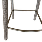 Close-up detail of the Myla counter stool highlighting the speckled light grey fabric and the curved antique brass metal footrest.