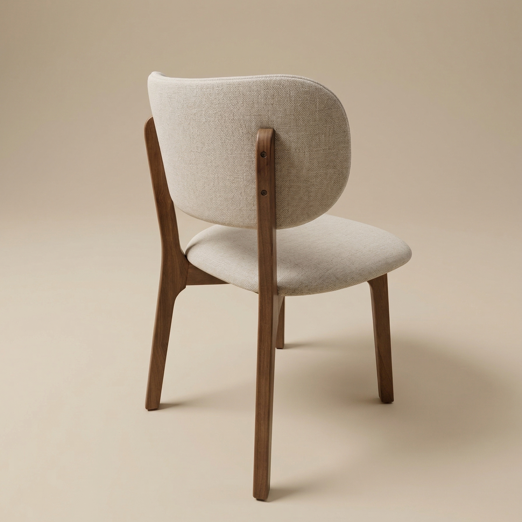Back view of the Nolan dining chair showcasing the seamless wood construction where the tapered legs meet the upholstered curved backrest.