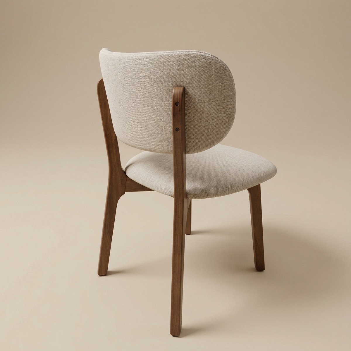 Back view of the Nolan dining chair showing the seamless wood construction where the tapered legs meet the upholstered curved backrest