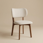 Angled view of the Nolan dining chair showing its elegant curved back silhouette and warm walnut-finished wood legs