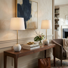 The white Nox marble orb lamps styled on a walnut console table with abstract art in a contemporary room.