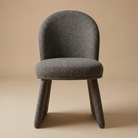 Front view of the Odette bouclé chair in charcoal color fabric showing its curved backrest and unique monolithic upholstered base
