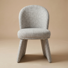 Front view of the Odette bouclé chair showing its curved backrest and unique monolithic upholstered base