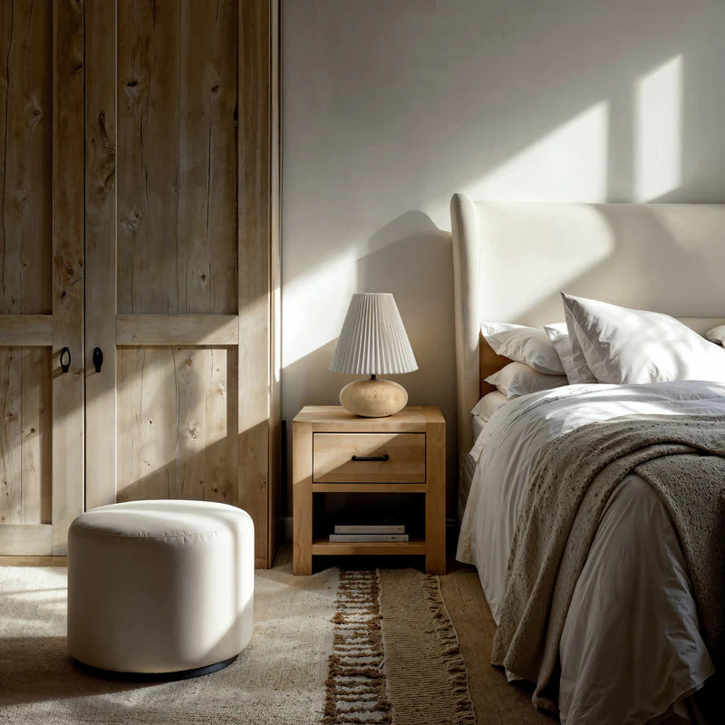 Cozy bedroom with wooden nightstand, lamp, and bed with white bedding.