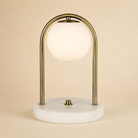 Table lamp with gold arch and marble base on a beige background