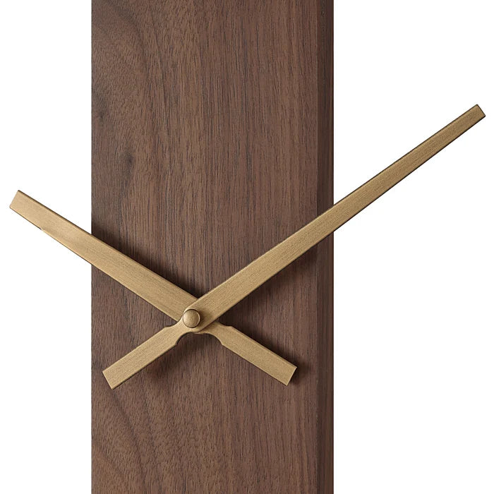 Close-up of the Orvella wall clock showing the antique brushed brass hands against the walnut wood panel.