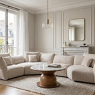 Modern living room with a beige sectional sofa, round wooden coffee table with marble top