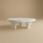 Pebble coffee table in white featuring a smooth organic shape and chunky tripod legs with a plaster-style finish.