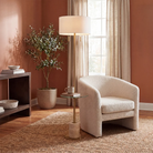 Perrin floor lamp styled beside a white lounge chair in a warm living room.