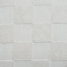 Macro close-up of the raised tufted knitted checkerboard texture on the cream Piper throw pillow.