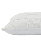 Close-up of the corner and thick knitted checkerboard fabric on the cream Piper throw pillow.