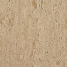 Close-up material swatch showing the natural pores and warm beige tones of Romina travertine