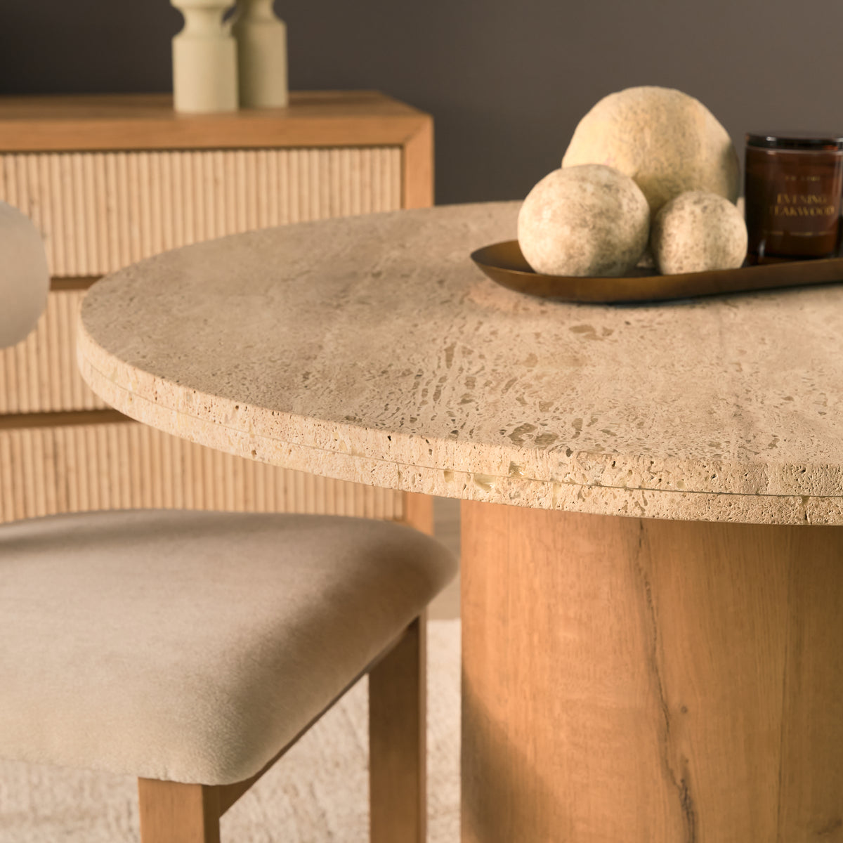 Styled close-up of the Romina travertine tabletop displaying its organic stone texture